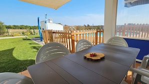 A patio with a table and chairs, a wooden fence, and a view of a pool and greenery. - Quinta da Bornacha (Vila Real Santo Antonio)