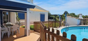 A poolside area with a wooden deck, a table with chairs, and a covered seating area. - Quinta da Bornacha (Vila Real Santo Antonio)