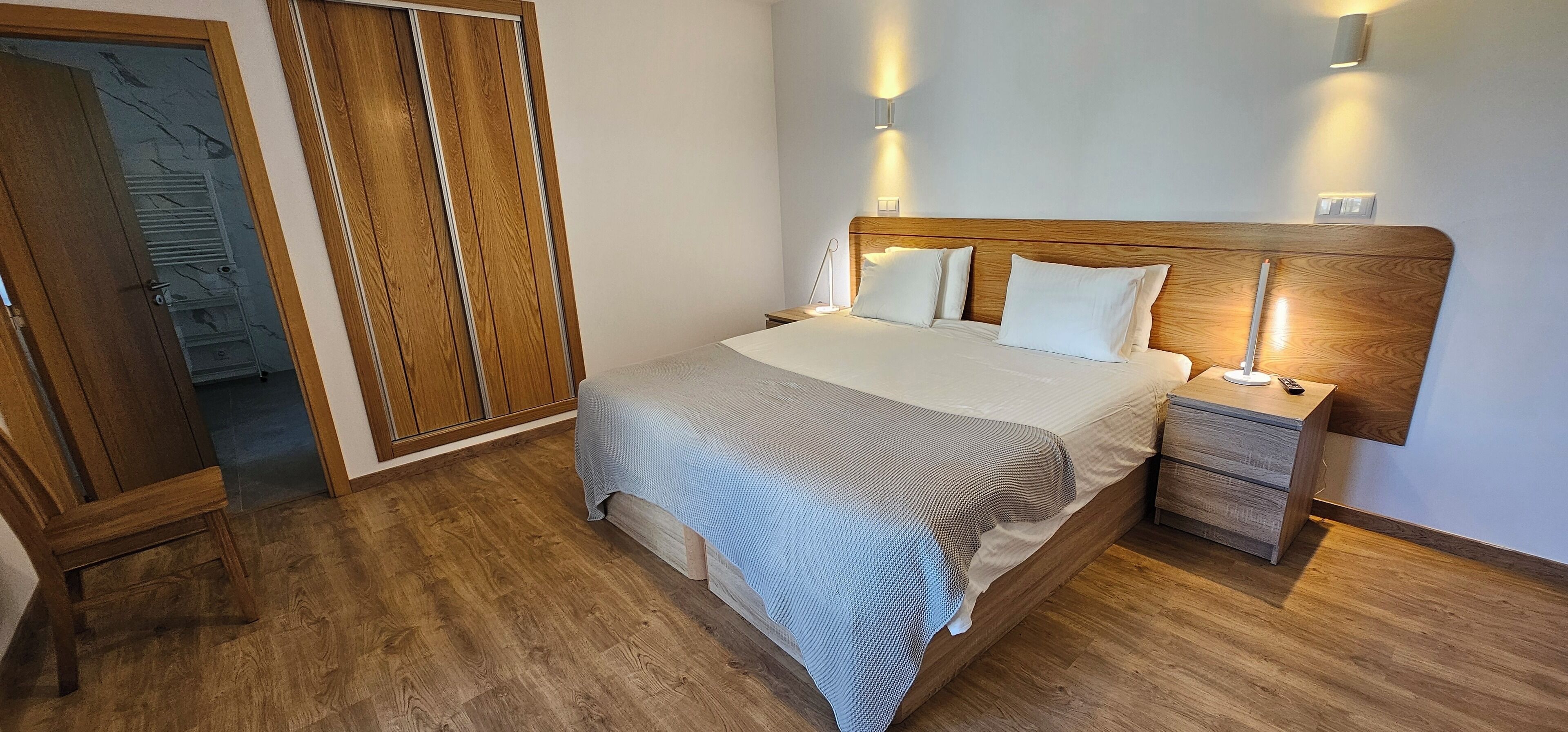 A bedroom with a wooden bed frame, a nightstand, and a wardrobe.