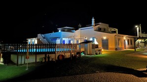 A modern building with a pool, a wooden deck, and a well-lit exterior at night. - Quinta da Bornacha (Vila Real Santo Antonio)