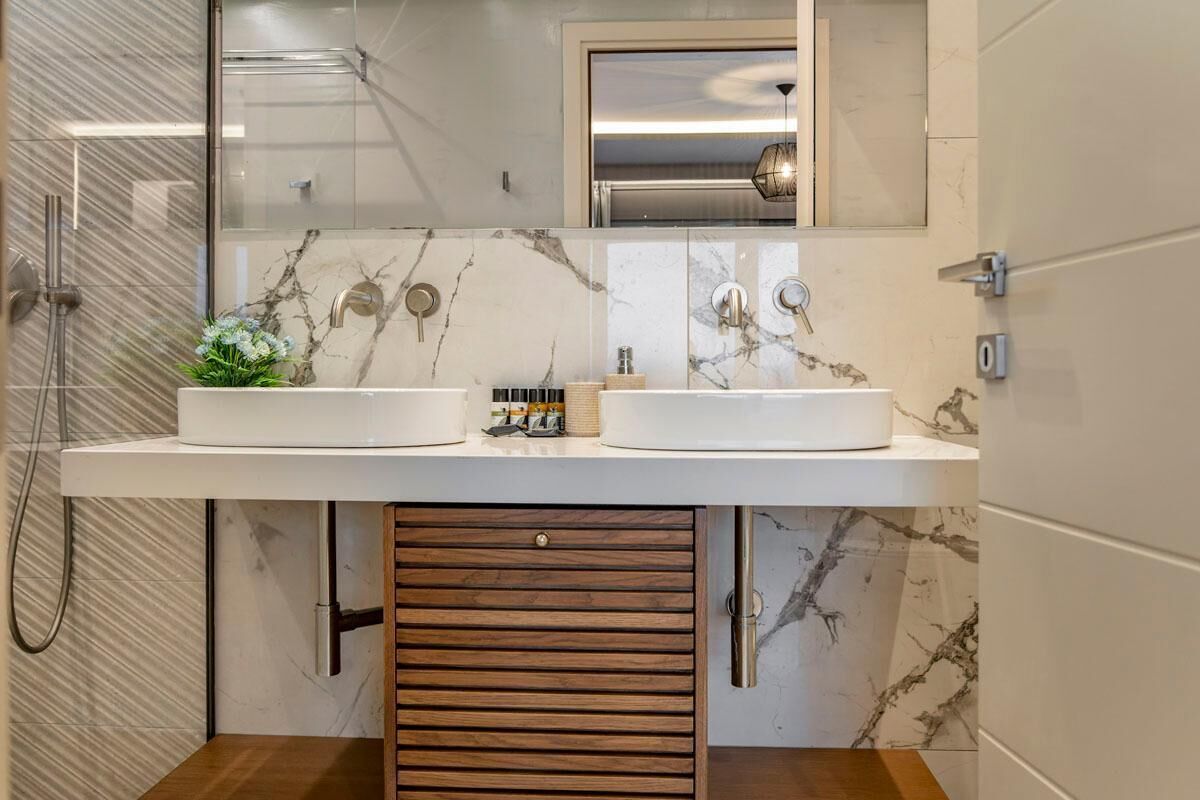 A bathroom with two sinks, a mirror, and a shower.
