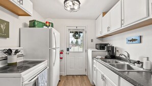 A compact kitchen with white cabinets, a microwave, a stove, and a sink.