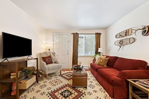 A living room with a television, a sofa, a chair, a coffee table, and a patterned rug.