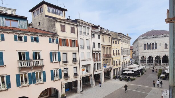 Une vaste place publique comprenant un espace café, des bâtiments historiques et une imposante structure en forme de dôme.