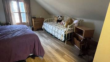 A bedroom with a bed, a desk, a chair, a dresser, and a window with curtains.