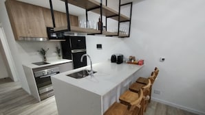 A modern kitchen with a central island, wooden bar stools, and a built-in oven. - Estudio en Palermo 4 (Buenos Aires)
