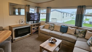 Ein gemütliches Wohnzimmer mit einer Couch, einem Couchtisch, einem Fernseher und einem Kamin.