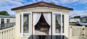 Una casa móvil con balcón, puerta corrediza de vidrio y un pequeño porche.
