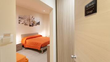 A hotel room with a bed, a nightstand, a wall-mounted artwork, and a sign indicating the room type and color theme.