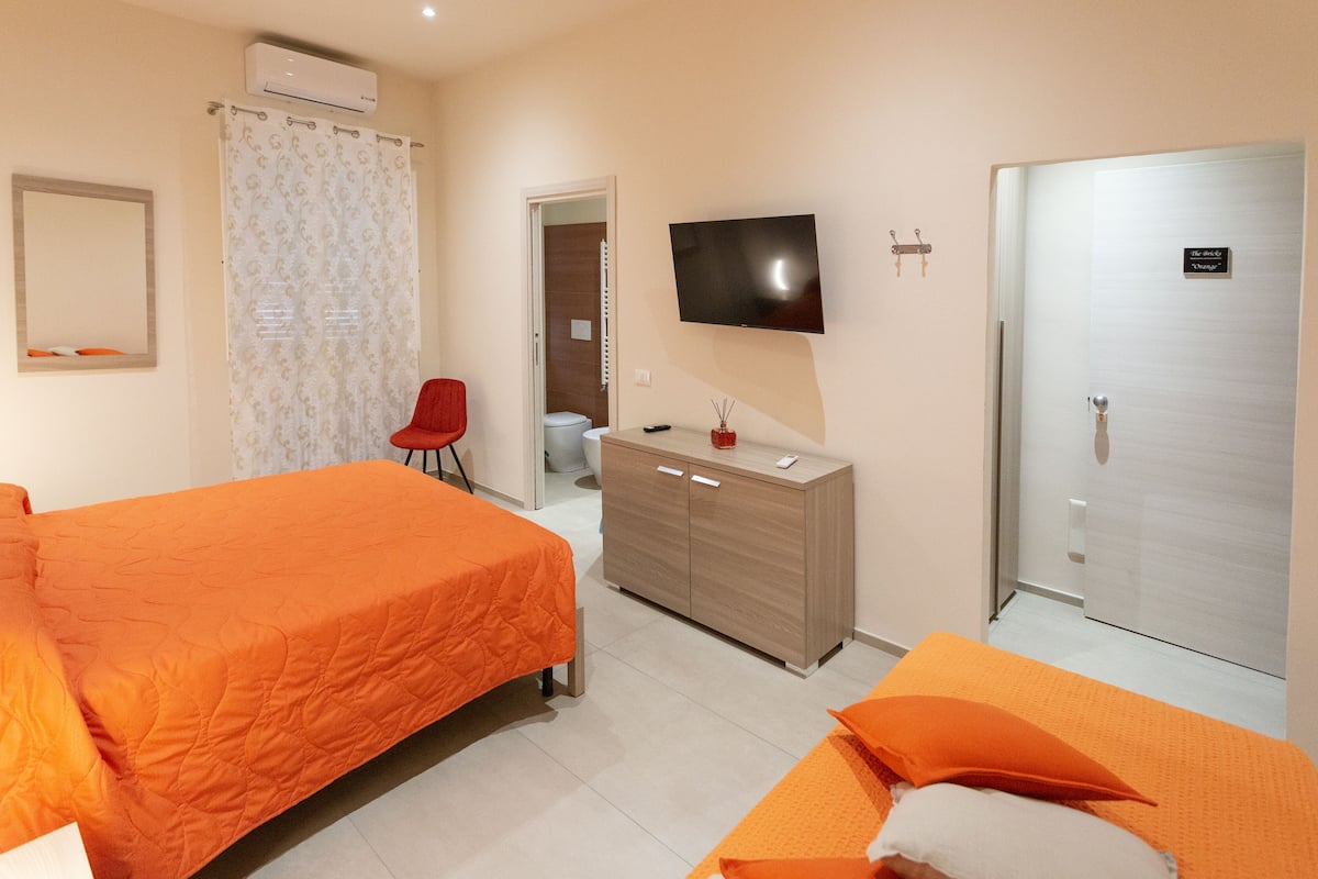 A hotel room with two beds, a TV, a wardrobe, and a bathroom.
