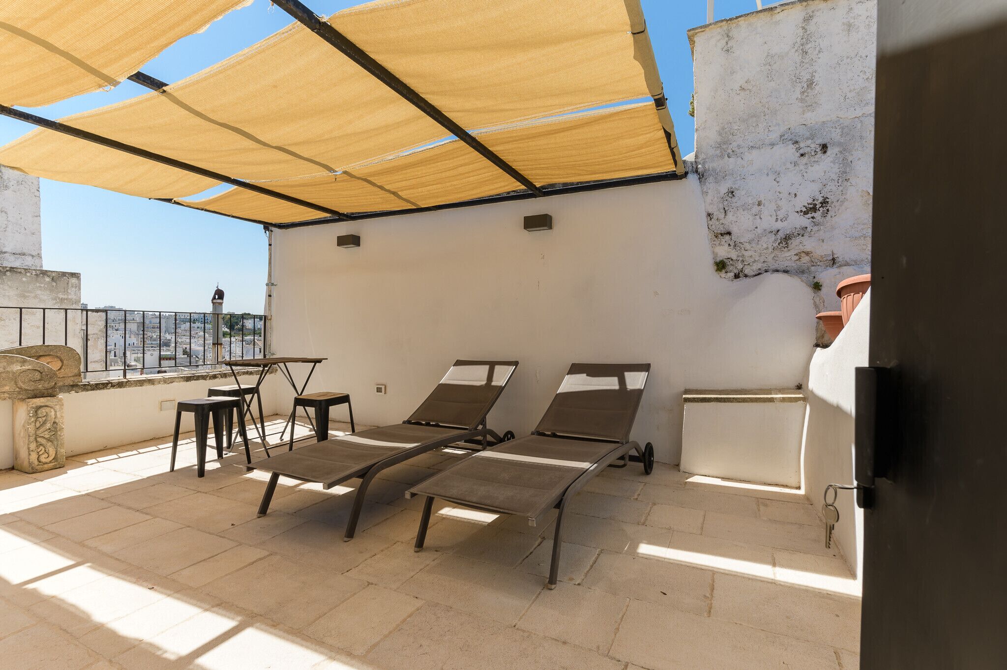 Eine Dachterrasse mit zwei Liegestühlen, einem kleinen Tisch und einem Stuhl.