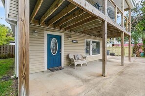 A house with a covered porch, a blue door, and a white chair. - Happy Daze Home, Fire Pit, Gazebo & Vilano Pier (St. Augustine)