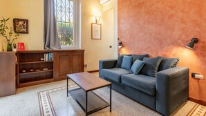Un salon avec un canapé, une table basse, une bibliothèque et une fenêtre avec des rideaux.