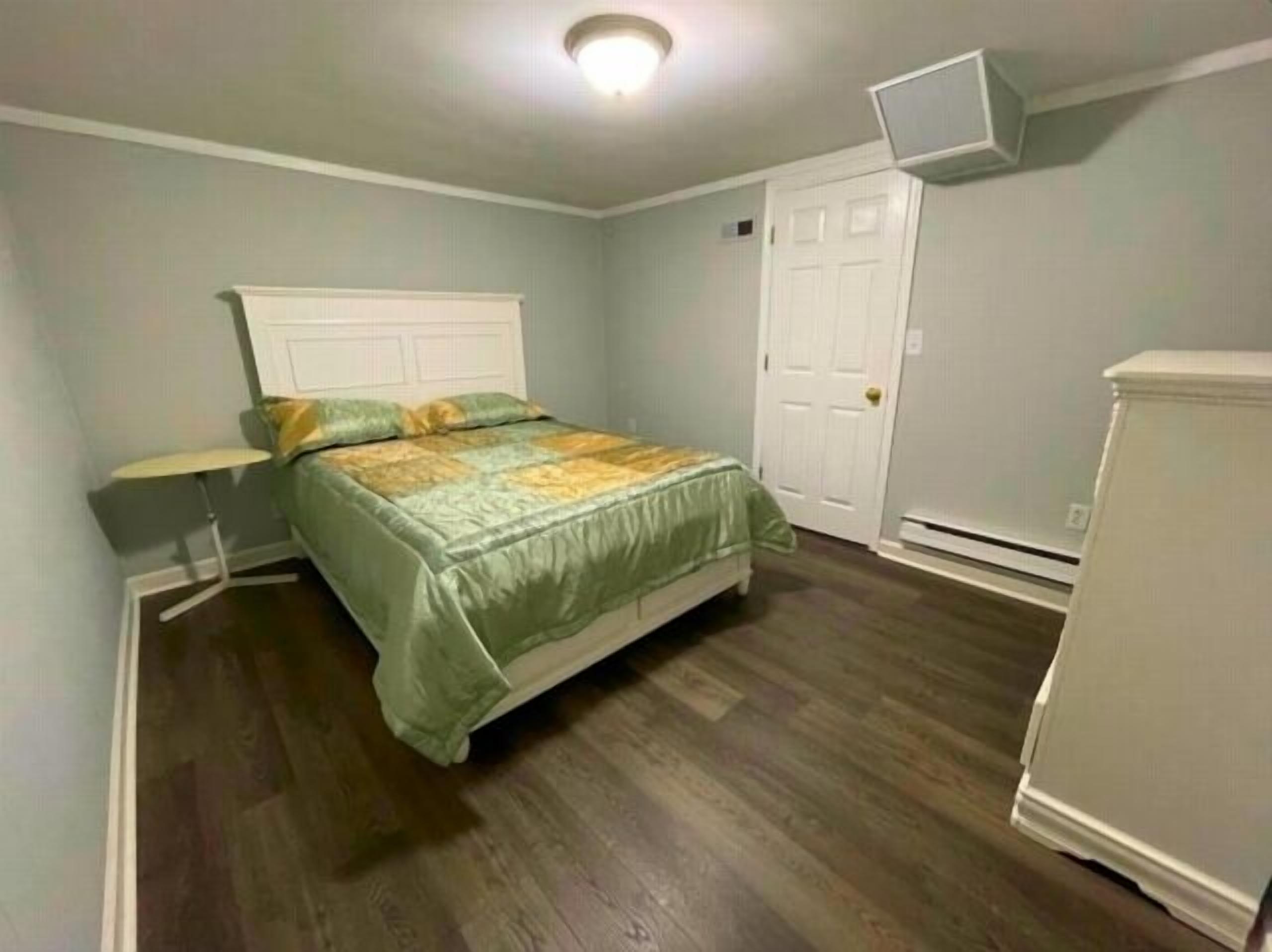 A bedroom with a bed, a nightstand, a dresser, and a white door.