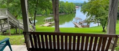 A wooden swing bench overlooking a lake with a dock and gazebo.