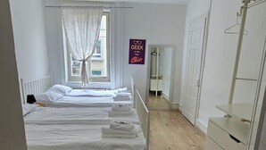 A bedroom with a single bed, a wardrobe, a mirror, and a window with curtains. - Mi Casa es su Casa (Zürich)