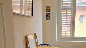 A dining area with a wooden table and chairs, a window with blinds, and a door with a brass handle. - Mi Casa es su Casa (Zürich)