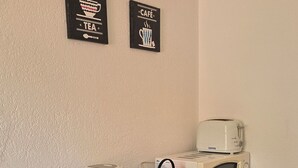 A kitchenette with a microwave, toaster, and kettle. There are two framed signs on the wall and a small refrigerator. - Mi Casa es su Casa (Zürich)