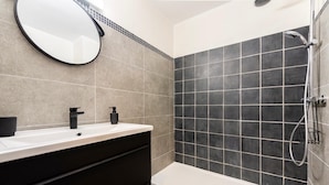 Een moderne badkamer met een wastafel, spiegel en douche.