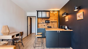Een moderne keuken met een houten eiland, zwarte kastjes en een donkere wand.