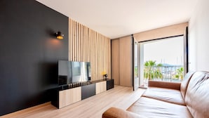 Een moderne woonkamer met een flatscreen televisie, een wand van houten latten en een groot raam met uitzicht op een jachthaven.