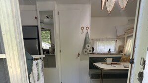 Eine kleine Küchenzeile mit Kühlschrank, Spüle und einem Fenster mit Vorhängen.