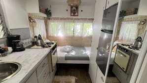 Eine kompakte Küchenzeile für Wohnmobile, ausgestattet mit Herd, Spüle und einem kleinen Bett mit Fenster.