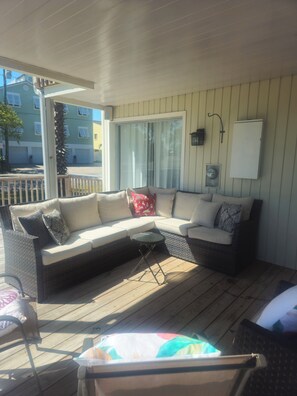 A covered outdoor seating area with a wicker sofa, a small round table, and a chair. - Spotless, newly remodeled home, 3 min walk to gorgeous Indian Rocks Beach! (Indian Rocks Beach)