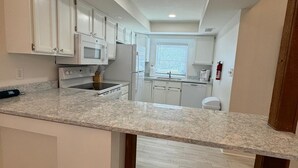Una cocina moderna con armarios blancos, encimera de granito y horno empotrado.