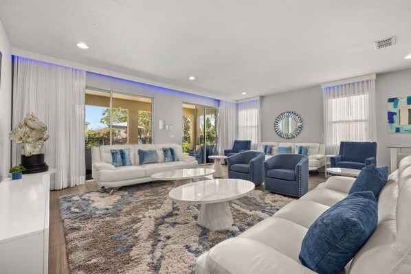 A modern living room with a white sofa, blue armchairs, and a coffee table.