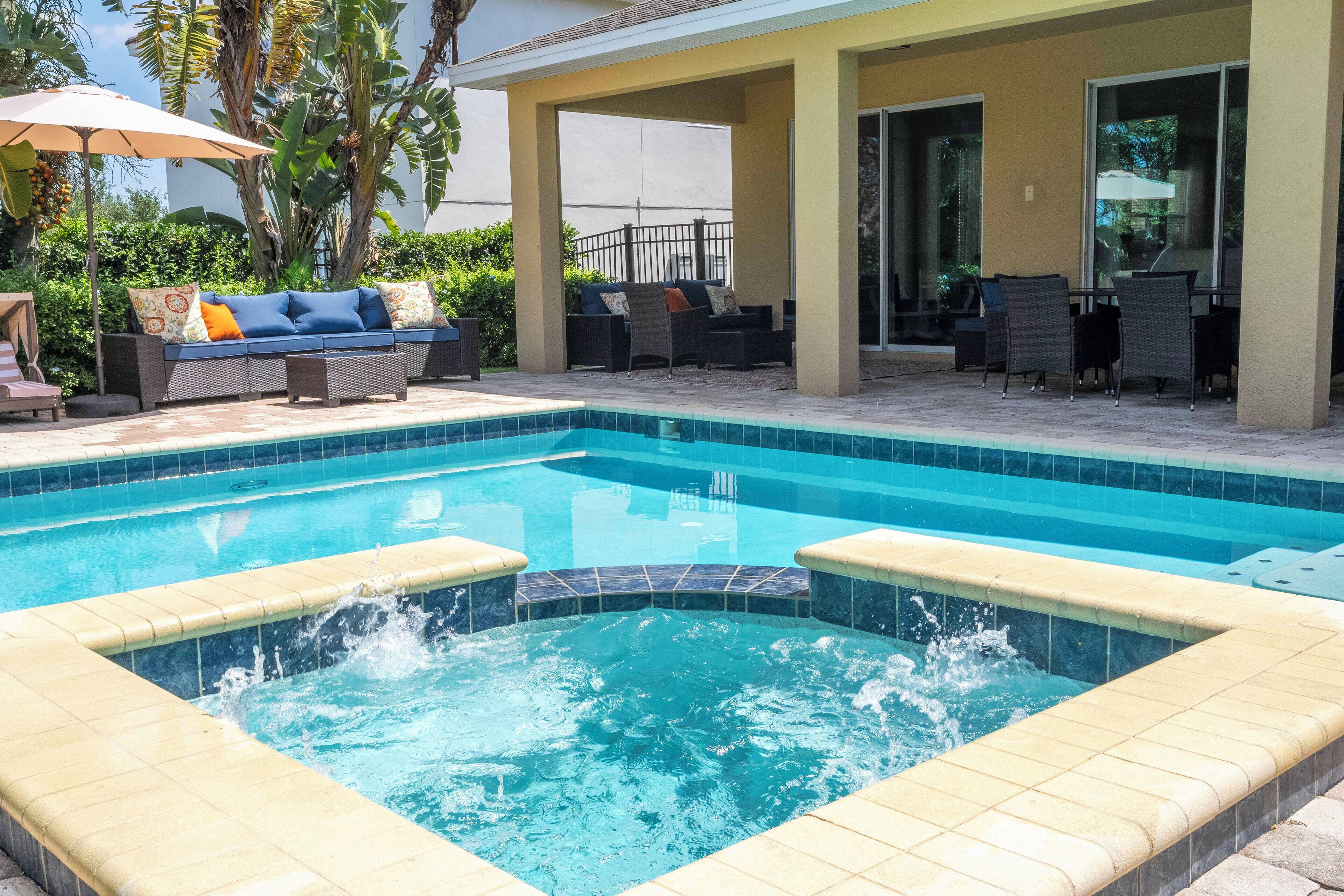 Una piscina con hidromasaje, rodeada de mobiliario exterior y una zona de estar cubierta.
