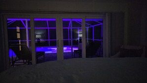 Una stanza con vista su un'area piscina, caratterizzata da un'ampia finestra a griglia e una sedia visibile in primo piano.