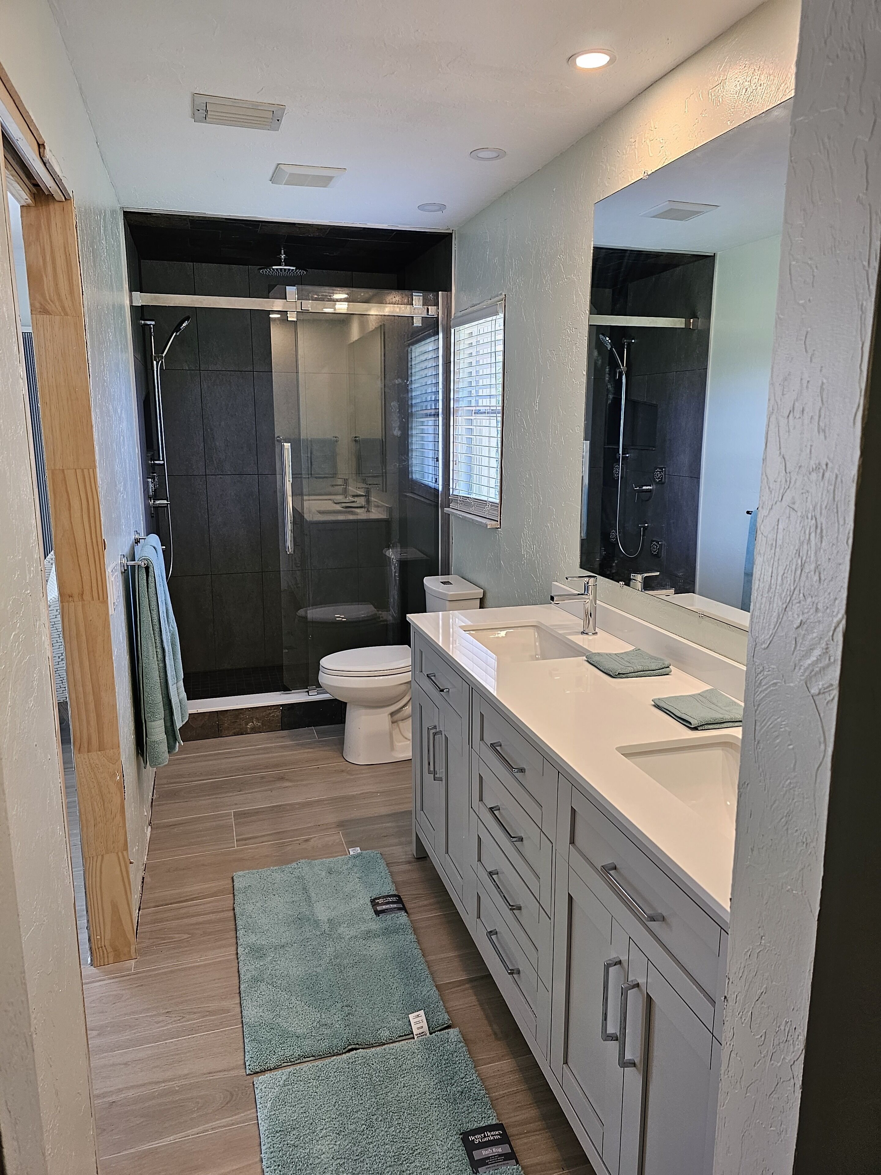 A modern bathroom with a walk-in shower, a toilet, and a vanity with a large mirror.