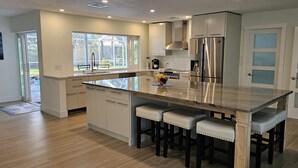 Una cucina moderna con una grande isola, elettrodomestici in acciaio inossidabile e vista sull'esterno.