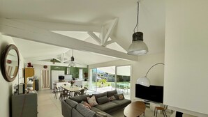 Ein modernes Wohnzimmer mit grauem Sofa, Essbereich und Küche.