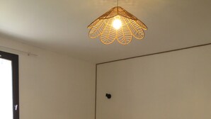 Un dormitorio con cama, suelo de madera, radiador blanco y lámpara colgante.