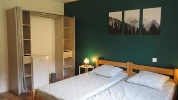 A bedroom with a bed, a wardrobe, a nightstand, and a wall-mounted lamp.