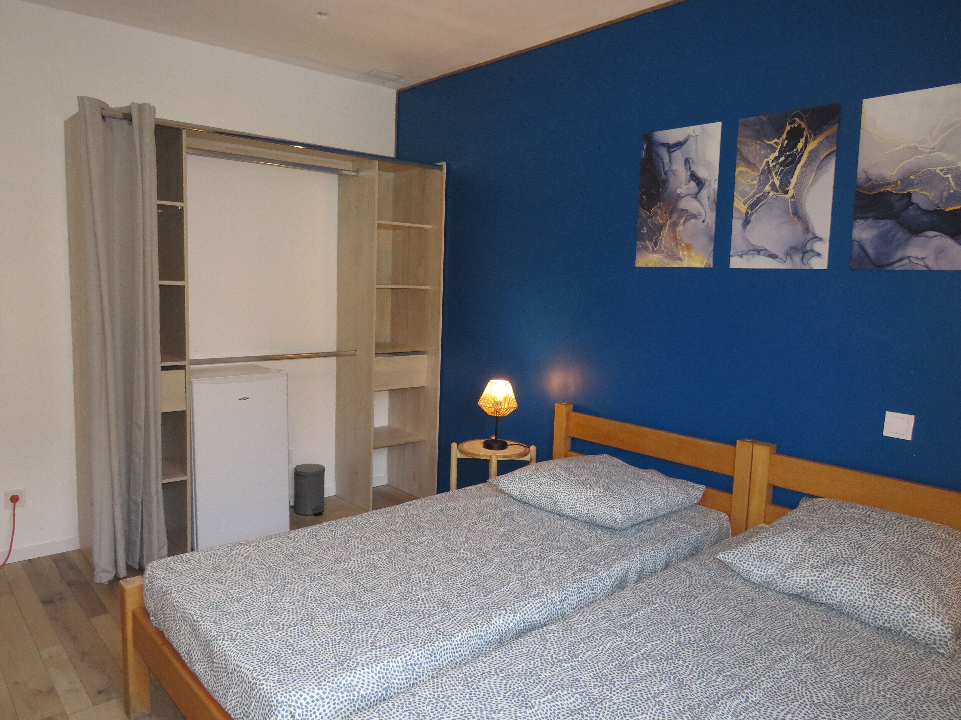 Un dormitorio con cama, armario, lámpara y una obra de arte en la pared.
