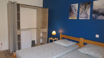 Un dormitorio con cama, armario, lámpara y una obra de arte en la pared.