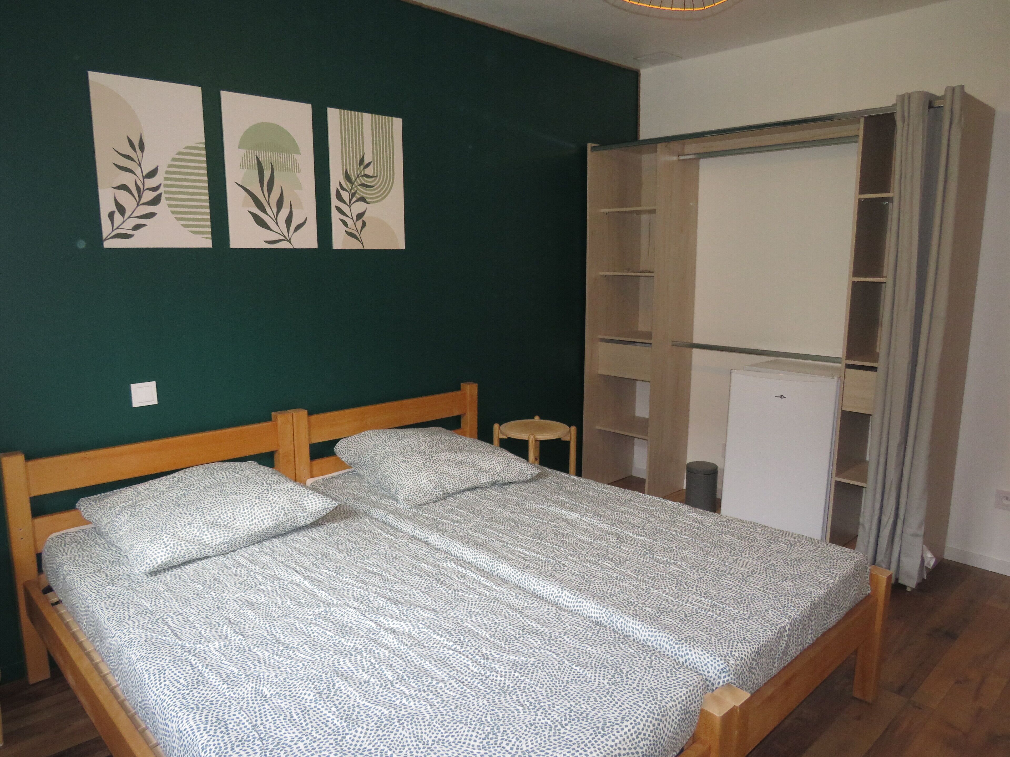 A room with a bed, a wardrobe, and a small table.