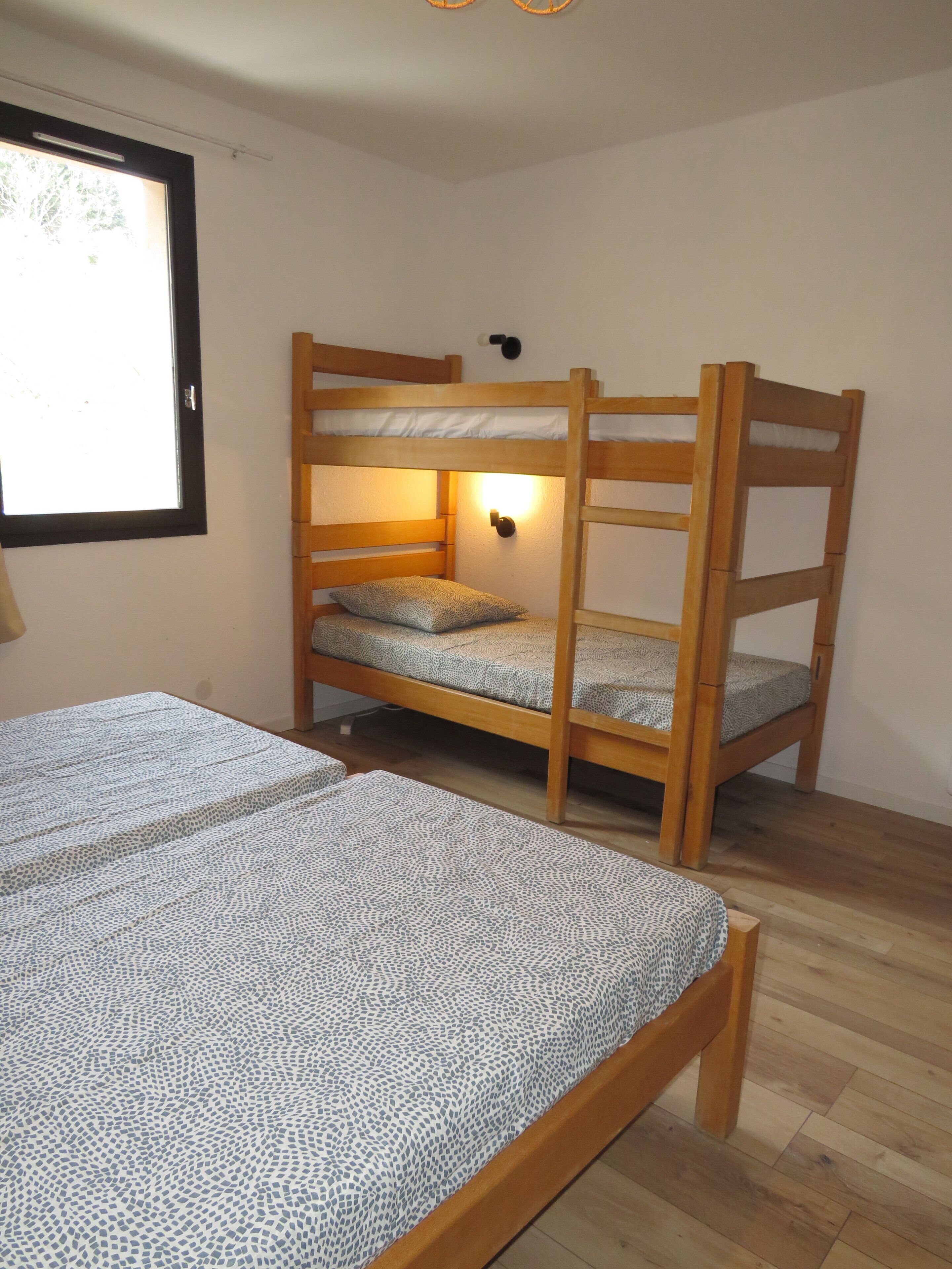 A bunk bed with a wooden frame and a single bed with a patterned bedspread.