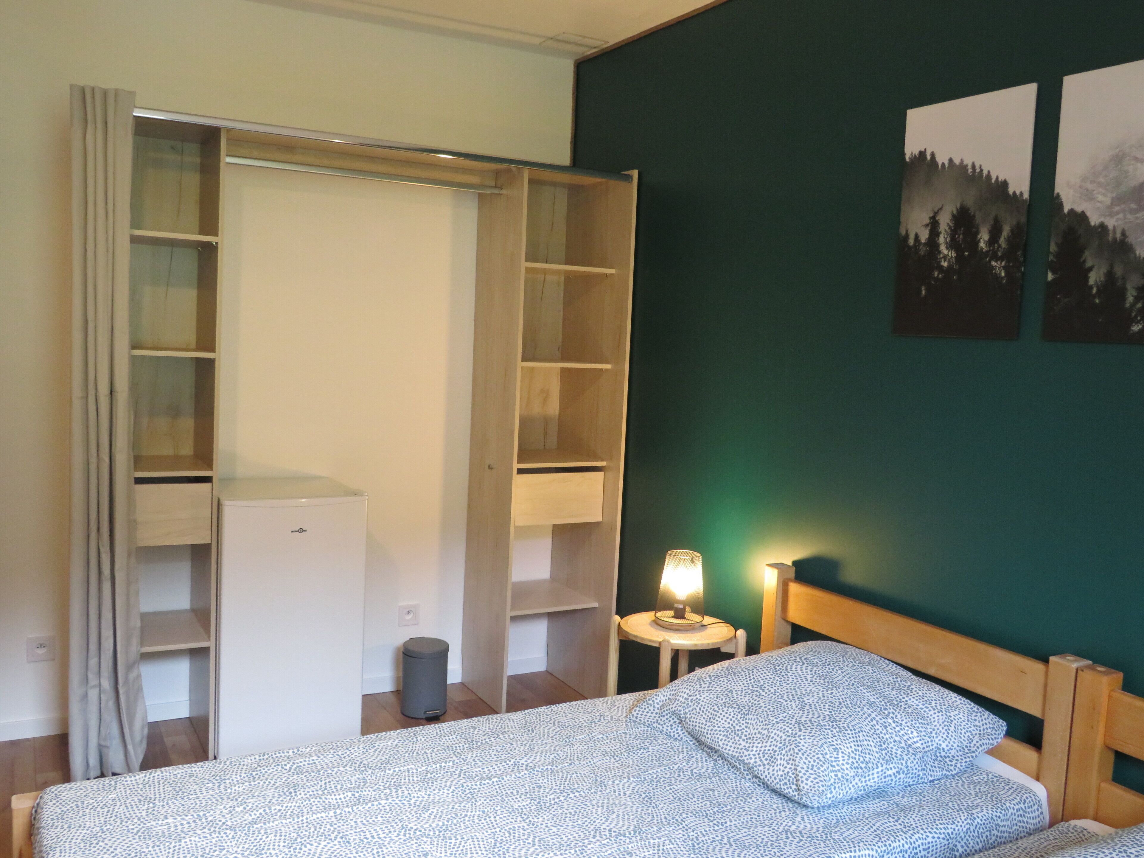 Een slaapkamer met een bed, een kledingkast, een nachtkastje en een lamp.