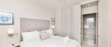A hotel room with a bed, a nightstand, a ceiling fan, and a door leading to a bathroom.