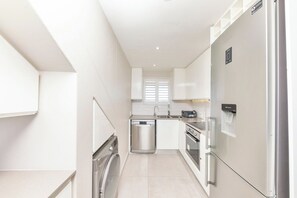 Cozinha compacta com lava-louças, forno e frigorífico.