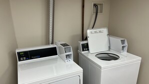 A compact laundry area with two white washing machines and a dryer, equipped with digital control panels.