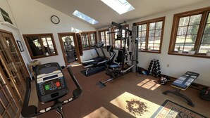 A gym with exercise equipment, a treadmill, and a bench.