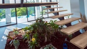 Ein modernes Interieur mit Treppe, Holzbanken und Topfpflanzen.