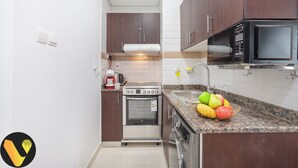 A modern kitchen with dark wooden cabinets, a stainless steel oven, a microwave, and a granite countertop.