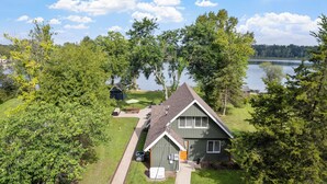 A house with a sloped roof, a covered porch, and a yard with a lawn and trees. - Murray Lake Waterfront Retreat w/ Dock, Patio & Fire Pit (Lowell)