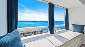 A balcony with a view of the sea, a bed with a view, and a window with curtains. - Ocean View 2BR Condo w/ Pool and Resort Access (Miami)